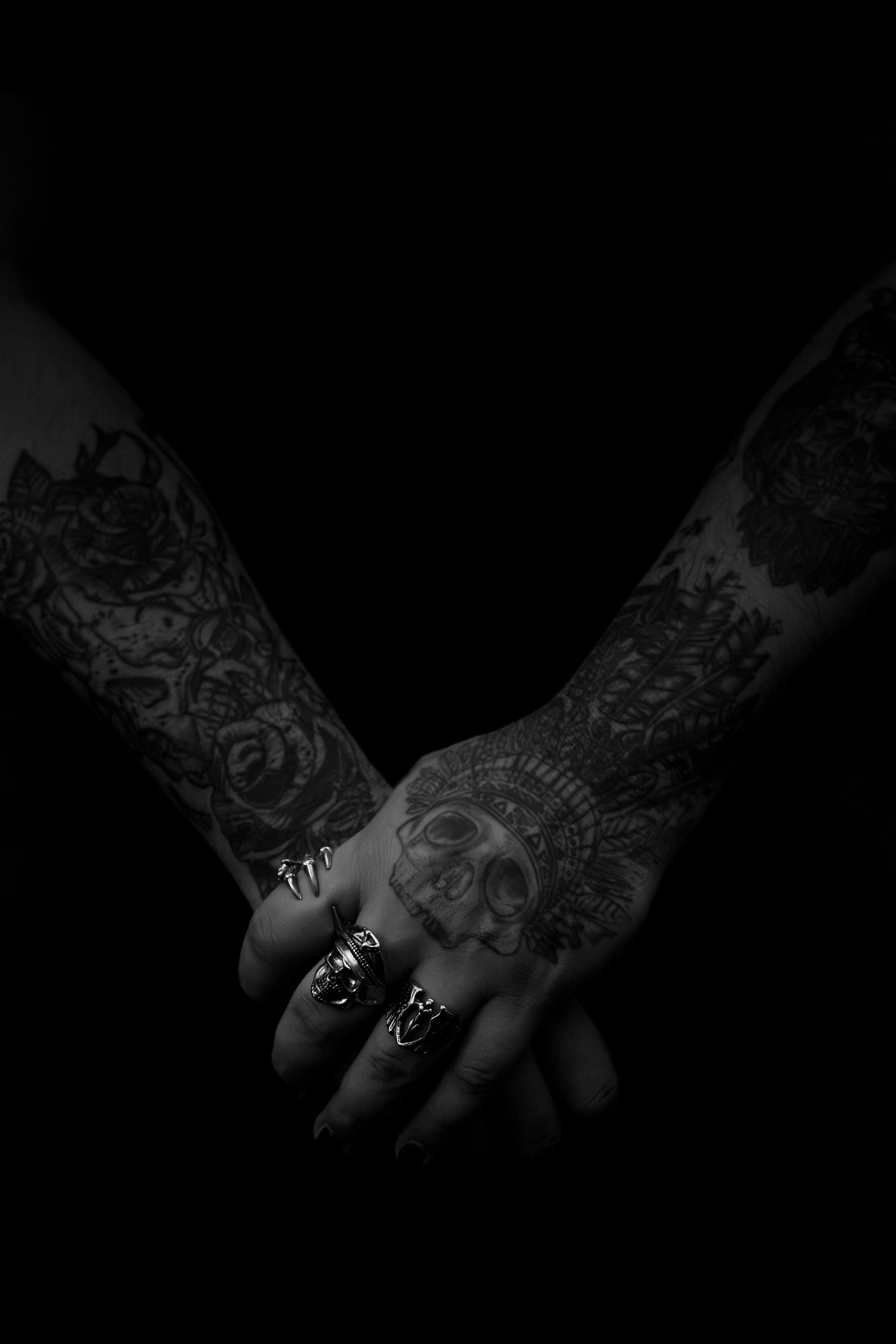 Two tattooed hands resting together in low light